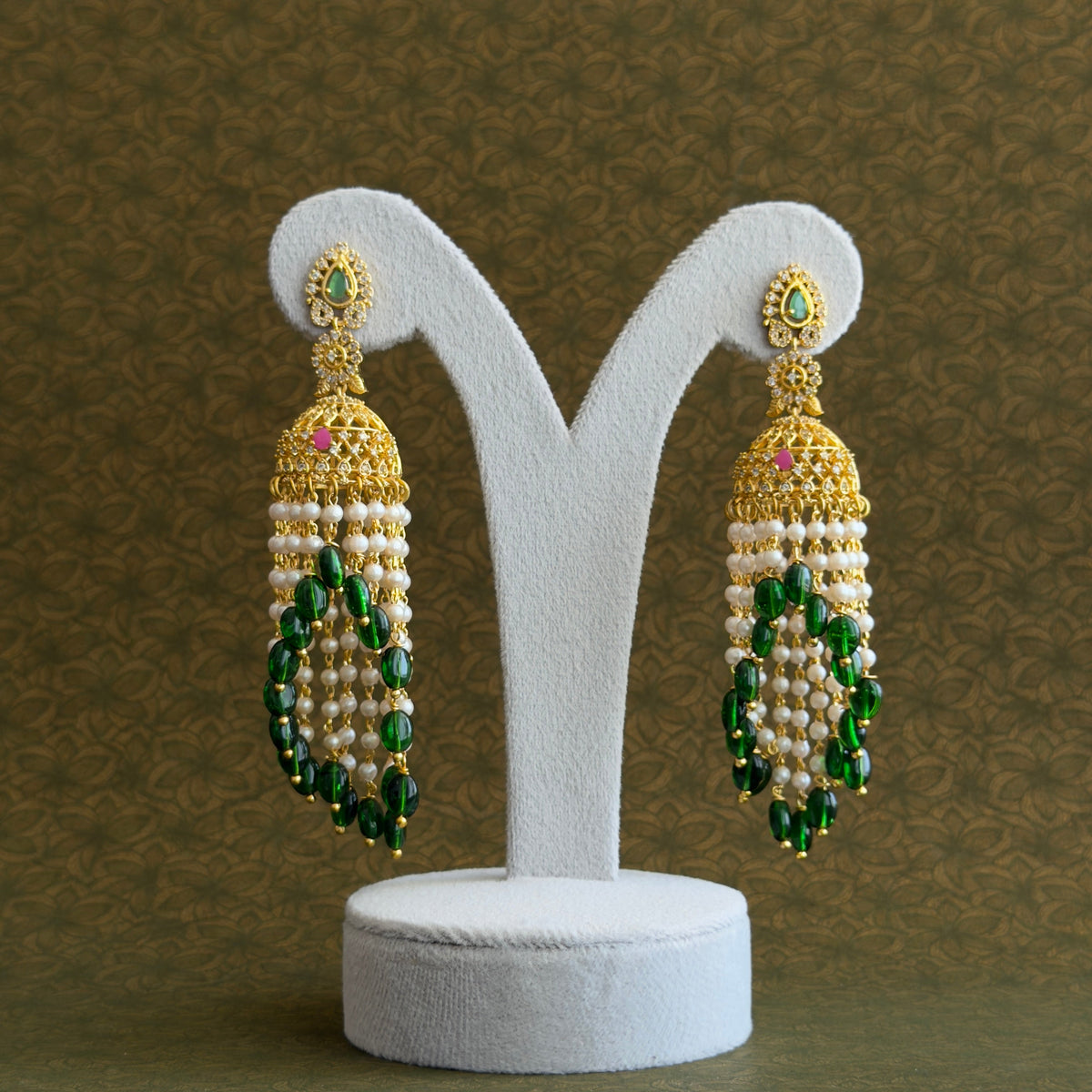 Waterfall earrings with cascading white beads and green drops against a dark backdrop