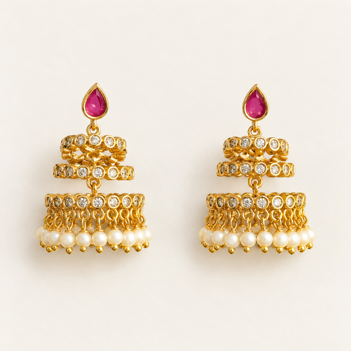 Pink teardrop tiered earrings with pearl-like drops held in a hand