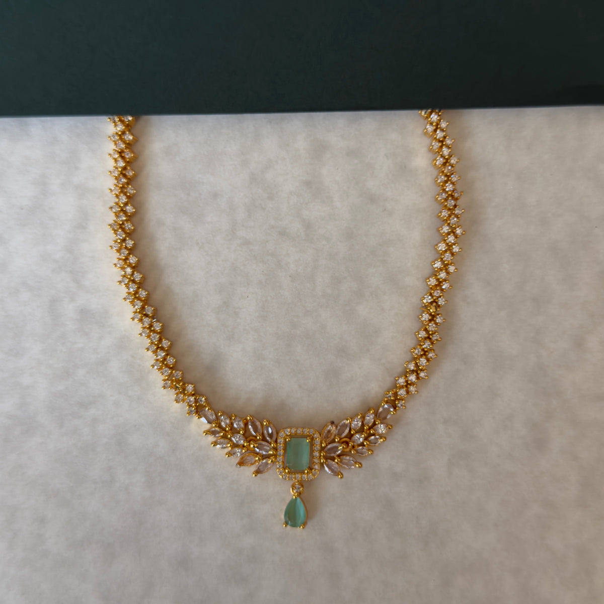 Gold-tone CZ necklace with mint green centre stone laid flat
