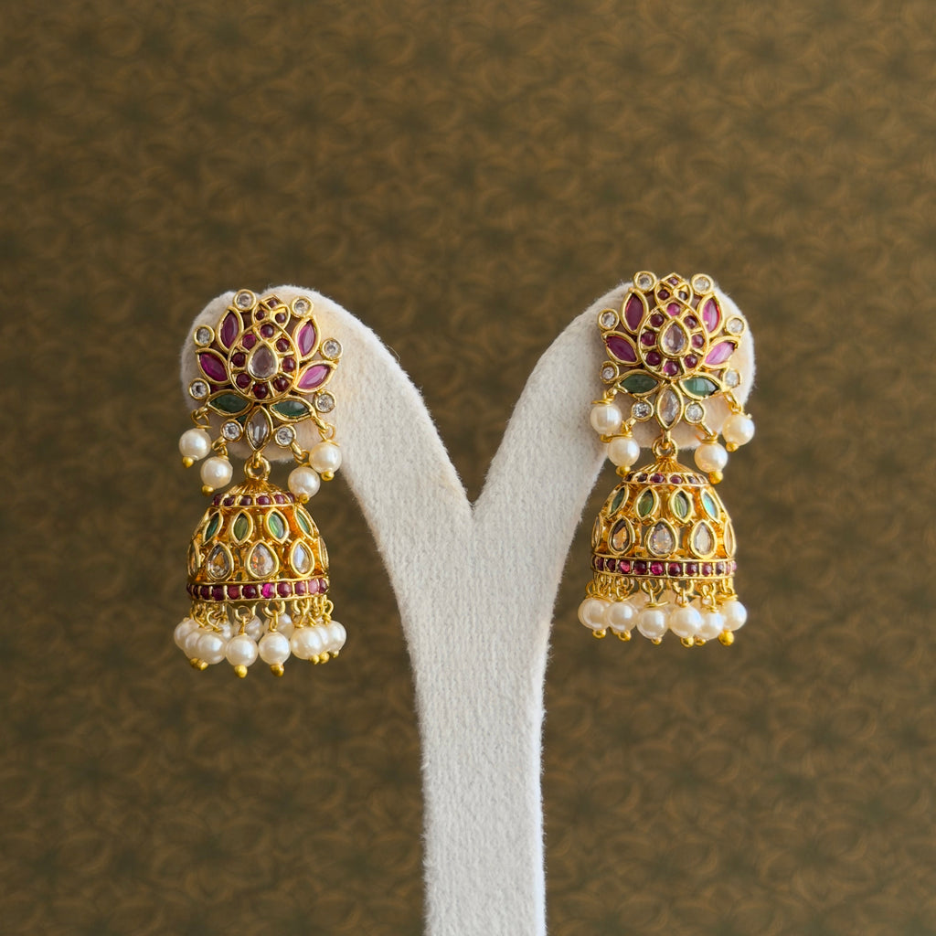 Pair of gold-tone multicolour jhumka earrings with pearl-like drops on a display stand